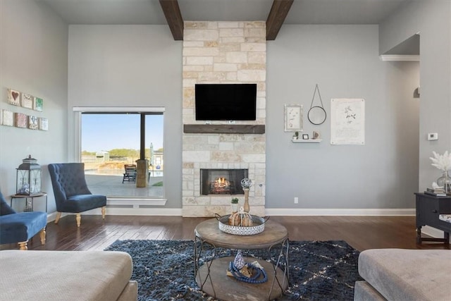 living room featuring a stone fireplace, beamed ceiling, and dark wood-type flooring