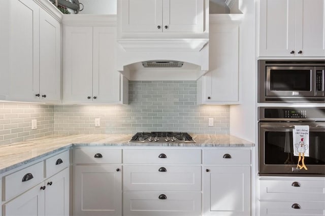 kitchen with decorative backsplash, light stone countertops, white cabinetry, and stainless steel appliances