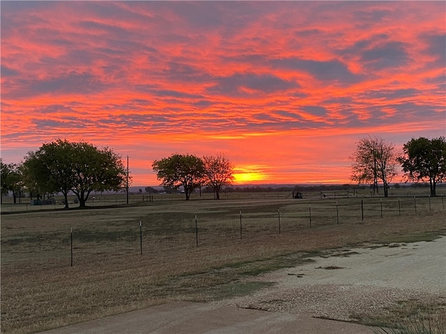 yard at dusk featuring a rural view