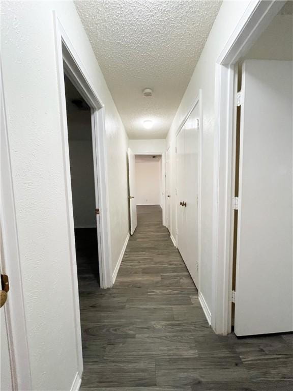 corridor with dark hardwood / wood-style flooring and a textured ceiling