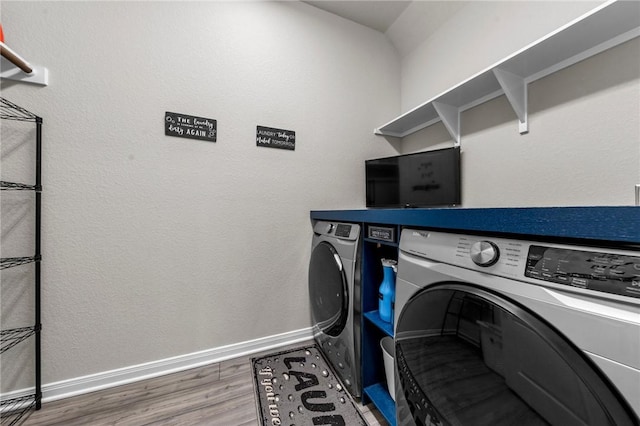 clothes washing area featuring dark wood-style floors, laundry area, independent washer and dryer, and baseboards