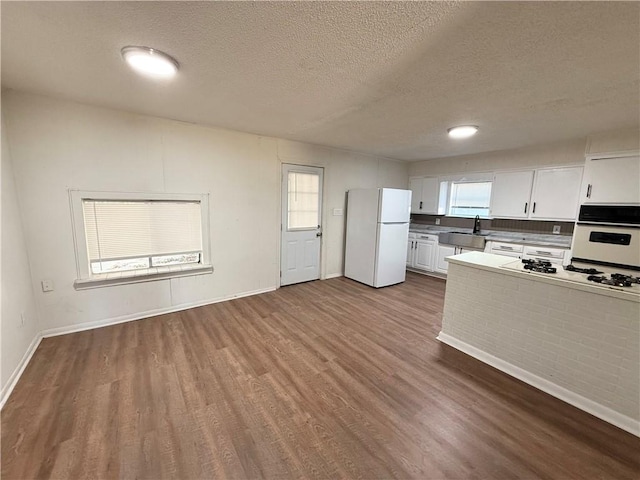 kitchen featuring white appliances, a textured ceiling, sink, hardwood / wood-style floors, and white cabinetry