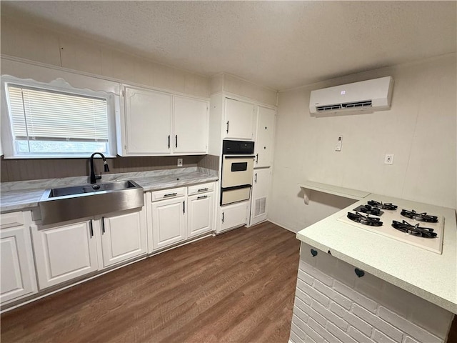 kitchen featuring a wall mounted air conditioner, white appliances, dark wood-type flooring, white cabinets, and sink