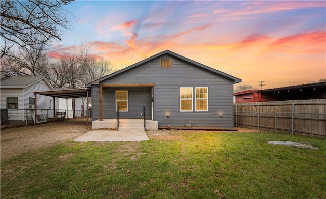 back house at dusk featuring a patio area and a lawn