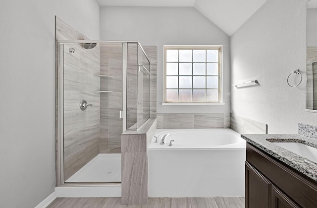 bathroom featuring shower with separate bathtub, vanity, hardwood / wood-style flooring, and lofted ceiling