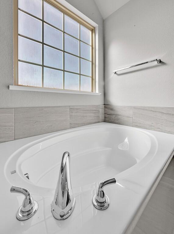 bathroom with a washtub and lofted ceiling