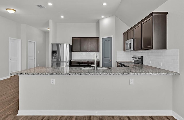 kitchen with dark hardwood / wood-style flooring, kitchen peninsula, sink, and appliances with stainless steel finishes