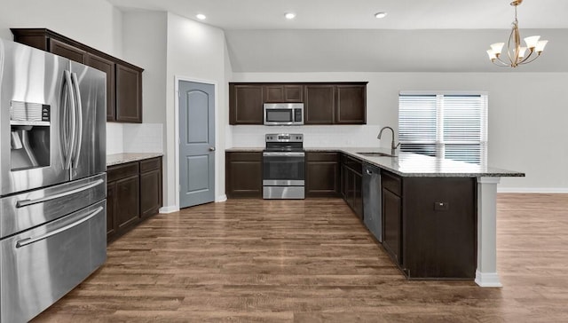 kitchen featuring an inviting chandelier, sink, dark hardwood / wood-style floors, appliances with stainless steel finishes, and light stone counters