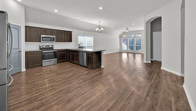 kitchen with dark wood-type flooring, ceiling fan with notable chandelier, sink, kitchen peninsula, and stainless steel appliances