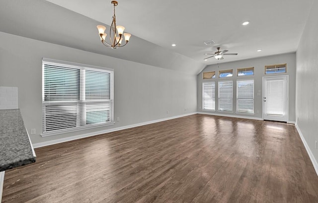 unfurnished living room with plenty of natural light, lofted ceiling, dark wood-type flooring, and ceiling fan with notable chandelier