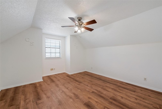 additional living space with hardwood / wood-style flooring, ceiling fan, a textured ceiling, and vaulted ceiling