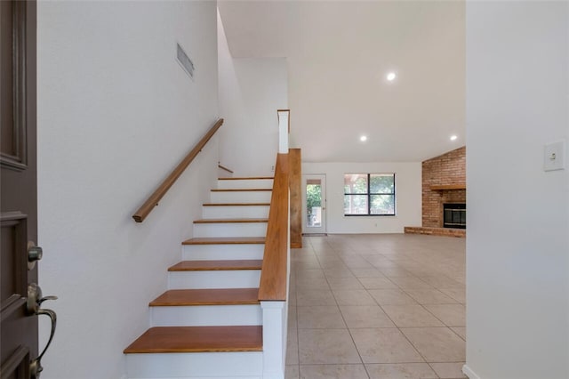 staircase featuring tile patterned floors, a fireplace, and vaulted ceiling