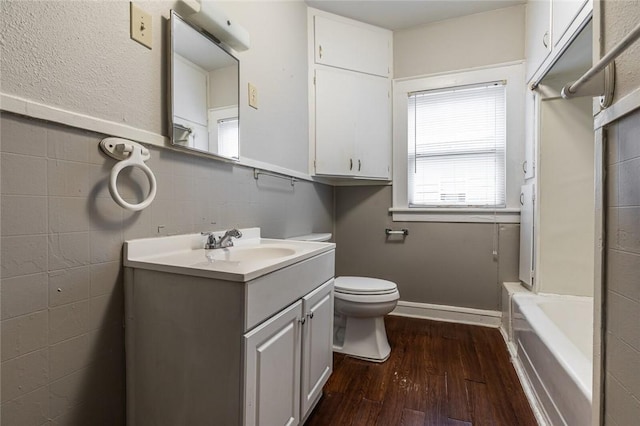 bathroom featuring vanity, a washtub, toilet, tile walls, and wood-type flooring