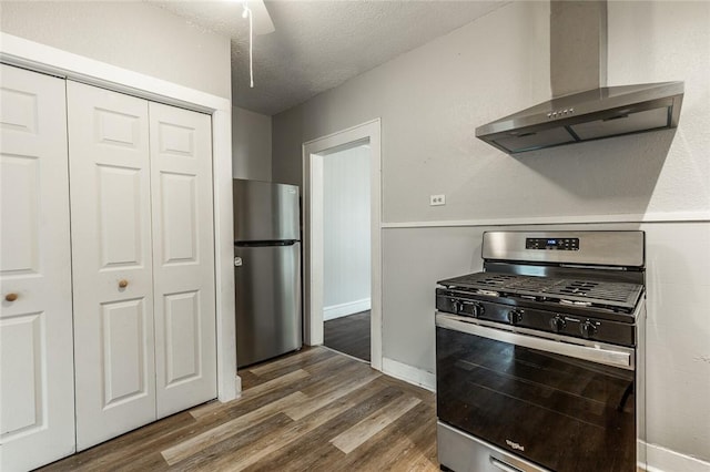 kitchen with a textured ceiling, dark hardwood / wood-style flooring, wall chimney range hood, and appliances with stainless steel finishes