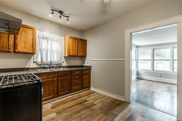 kitchen with electric range, sink, light hardwood / wood-style floors, and a textured ceiling