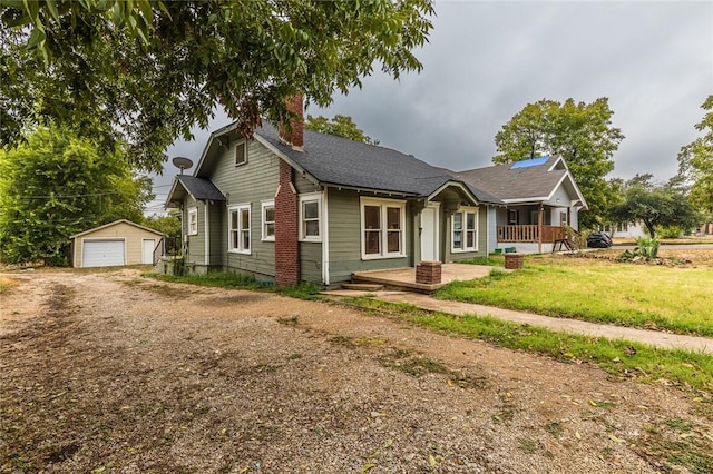 view of front of home with an outbuilding, a porch, a garage, and a front lawn