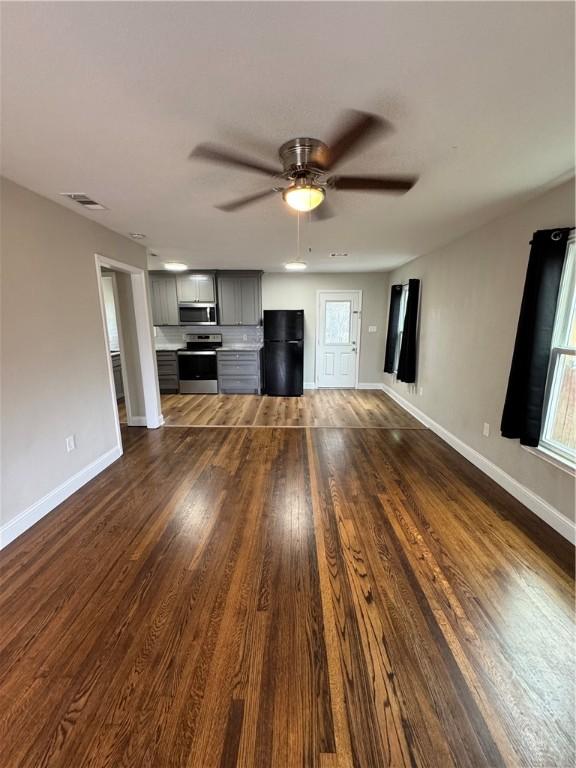 unfurnished living room with ceiling fan and dark wood-type flooring