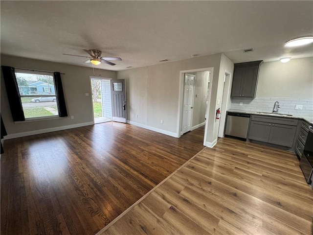 unfurnished living room with ceiling fan, wood-type flooring, and sink