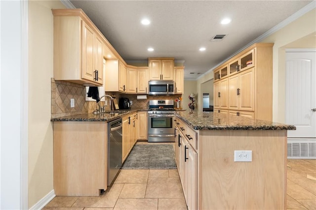 kitchen featuring light brown cabinets, visible vents, a kitchen island, a sink, and appliances with stainless steel finishes