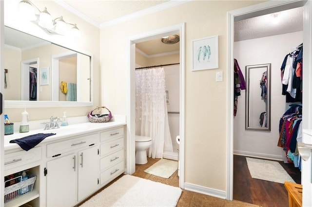 bathroom with a walk in closet, crown molding, toilet, tile patterned floors, and vanity