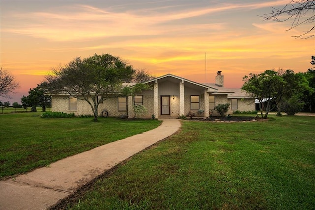 mid-century inspired home featuring brick siding, a chimney, and a front lawn