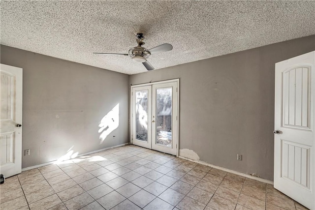 spare room with a textured ceiling, light tile patterned flooring, a ceiling fan, and baseboards