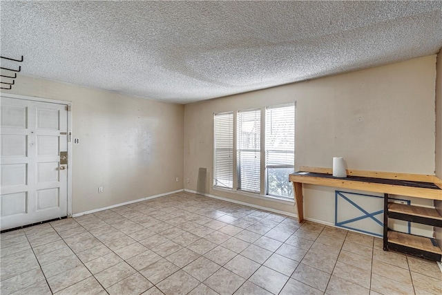 interior space with light tile patterned floors, baseboards, and a textured ceiling