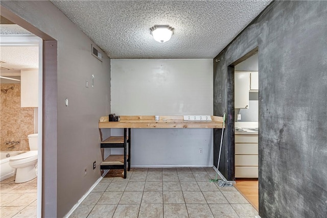 interior space with light tile patterned floors, light countertops, and a textured ceiling