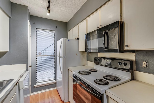 kitchen featuring white appliances, white cabinets, light countertops, a textured ceiling, and light wood-type flooring