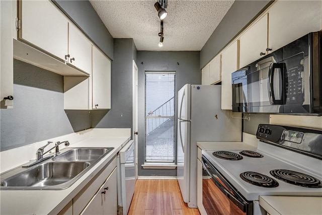 kitchen featuring black microwave, white cabinetry, range with electric stovetop, and a sink