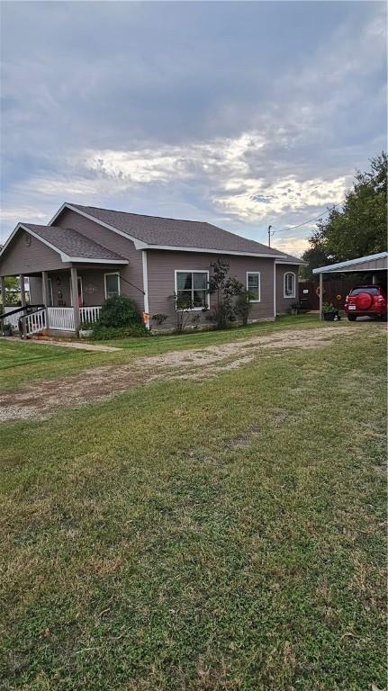 view of front of home with a front lawn, a porch, and a carport