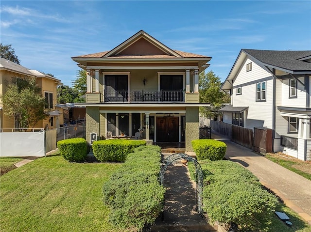 view of front of house with a front yard, fence, and a balcony