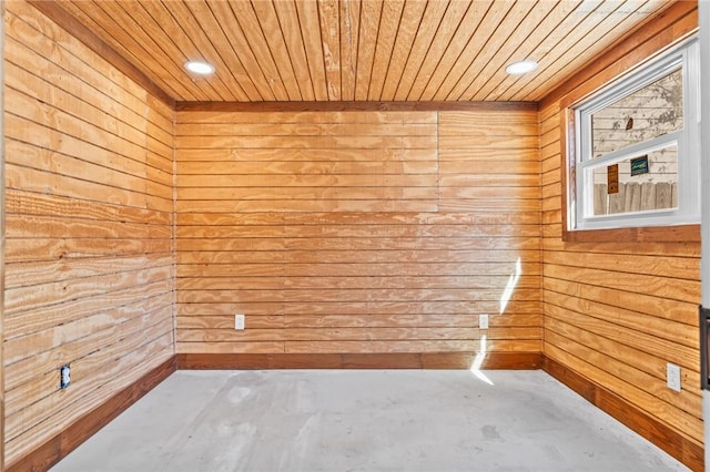 unfurnished room featuring wooden walls, concrete floors, and wood ceiling