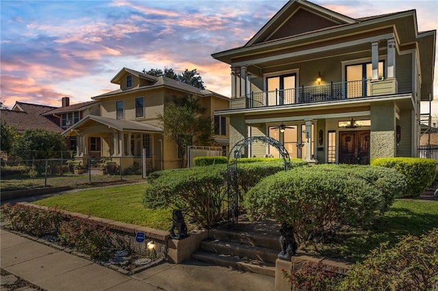 view of front of property featuring a balcony, fence, and a front yard