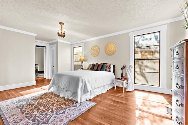 bedroom featuring a textured ceiling, an inviting chandelier, wood finished floors, and crown molding