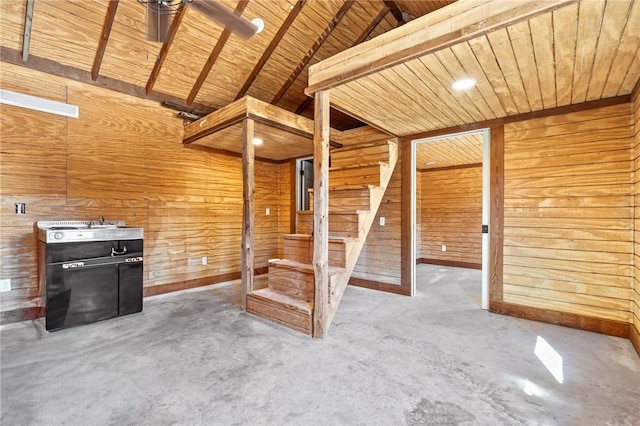 unfurnished living room with lofted ceiling with beams, wood walls, wooden ceiling, and concrete floors