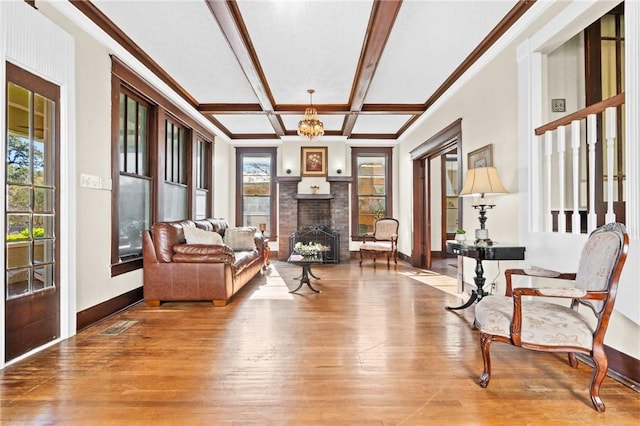 living area with coffered ceiling, beamed ceiling, a chandelier, wood-type flooring, and a fireplace