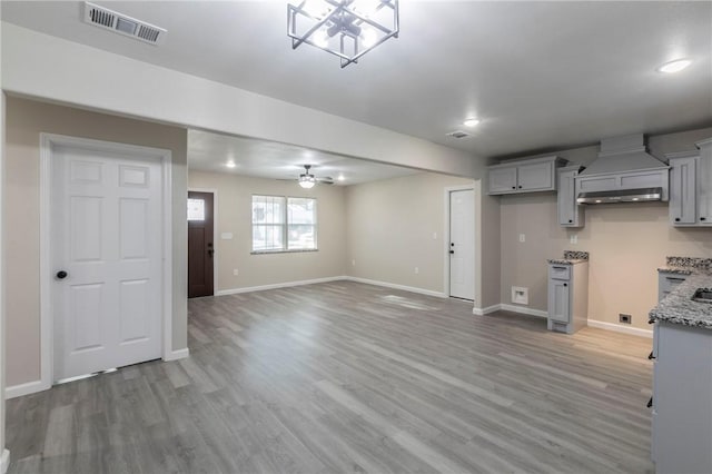 interior space featuring hardwood / wood-style floors, premium range hood, light stone countertops, and gray cabinetry