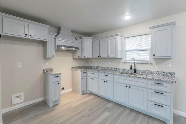 kitchen featuring light stone countertops, sink, and light wood-type flooring