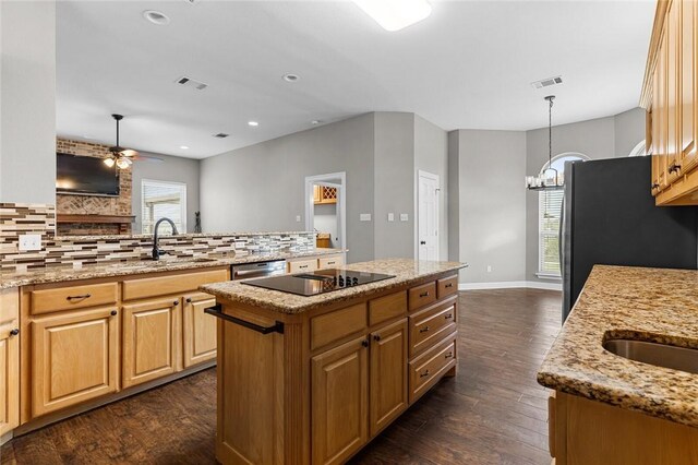 kitchen with black appliances, ceiling fan with notable chandelier, dark hardwood / wood-style floors, light stone countertops, and a kitchen island