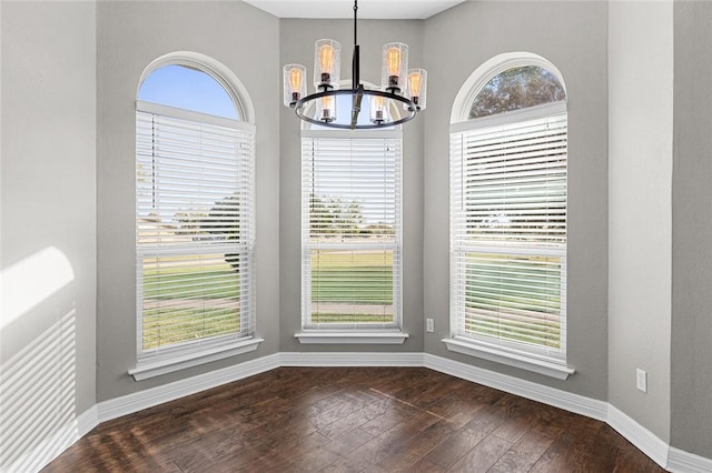 unfurnished dining area featuring plenty of natural light, dark hardwood / wood-style floors, and a chandelier