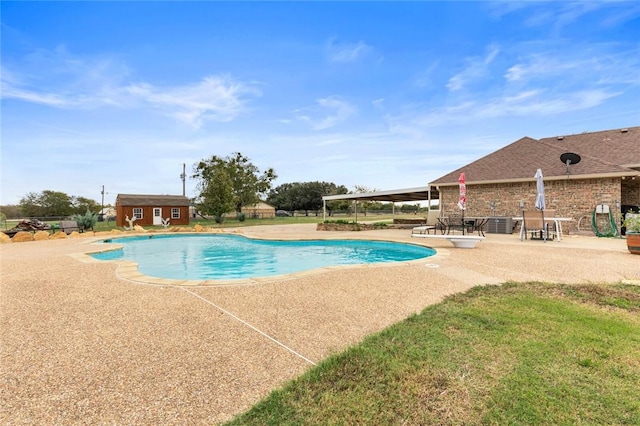 view of swimming pool featuring an outbuilding and a patio