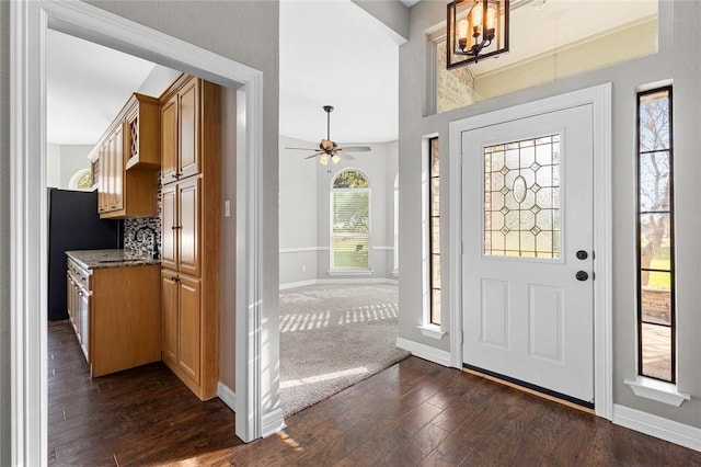 entrance foyer featuring ceiling fan with notable chandelier, dark hardwood / wood-style flooring, and vaulted ceiling