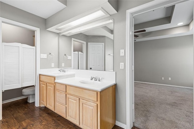 bathroom with hardwood / wood-style floors, vanity, ceiling fan, and toilet