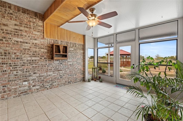 unfurnished sunroom featuring ceiling fan and a healthy amount of sunlight