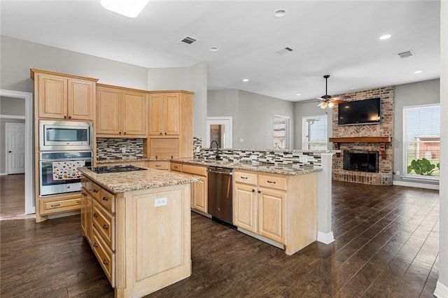 kitchen with kitchen peninsula, appliances with stainless steel finishes, a wealth of natural light, and light brown cabinetry