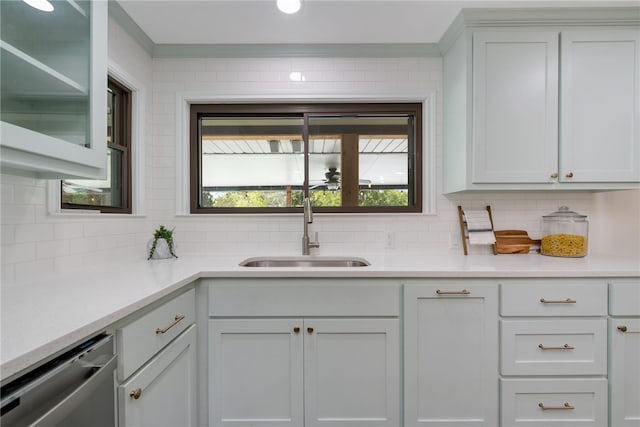 kitchen featuring stainless steel dishwasher, decorative backsplash, white cabinets, and sink