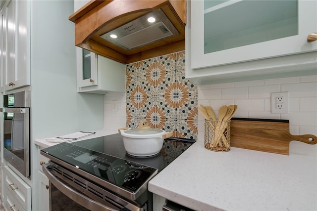 kitchen with stainless steel appliances, white cabinetry, tasteful backsplash, and custom exhaust hood