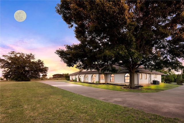 view of front of property with a yard and central AC