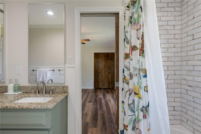 bathroom with hardwood / wood-style floors, vanity, crown molding, and brick wall